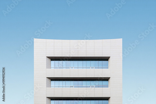 Modern building facade with geometric patterns against clear blue sky