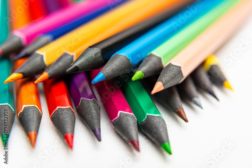 Colorful pencils arranged in a pile on a white surface with sharp tips ready for drawing and coloring