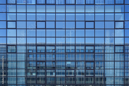 Glass facade of a modern building reflecting blue sky
