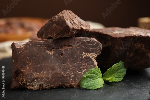 Foto Natural chocolate chunks and mint on table, closeup