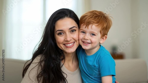 Happy mother and young son with red hair smiling together. Portrait of a woman and her child bonding at home. Family love and happiness concept