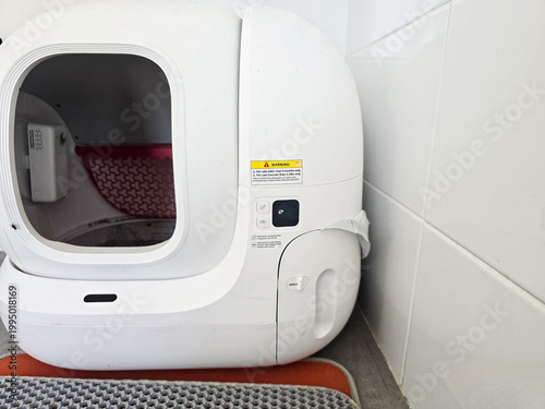 Modern automatic self-cleaning cat litter box placed on a tiled floor with a mat. Concepts of pet care technology, home convenience, and smart living solutions.