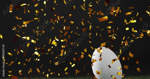 Falling metallic gold confetti filling dark stage over turf, white oval ball resting, copy space