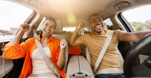 Fényképezés Happy young African American couple celebrating success inside car, raising fist