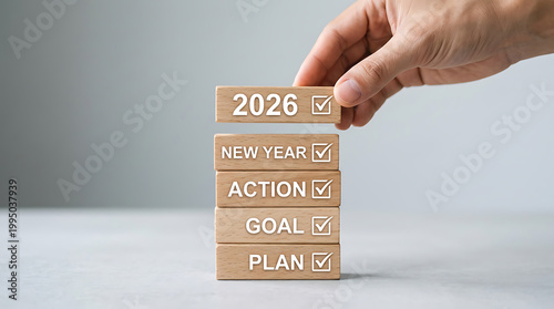 Hand placing 2026 block on New Year goal action plan list