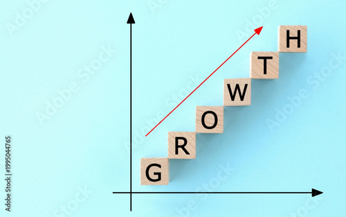 Business growth chart with wooden blocks spelling growth on a light blue background with a red upward trend arrow