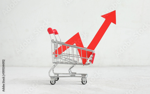 Shopping cart with rising red arrow graph indicating sales growth and economic increase on white background