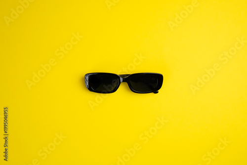 black sunglasses on yellow background. Copy space.