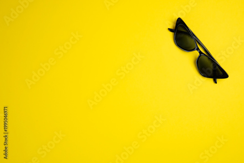 black sunglasses on yellow background. Copy space.