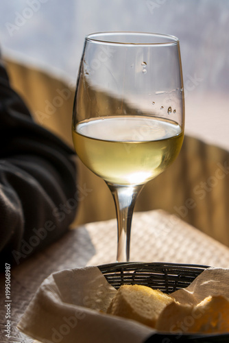 glass of white wine and basket of bread on a restaurant table in Spain