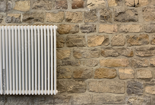 Heating radiator on a stone wall with empty space on the right. Minimal interior background for web or banner design