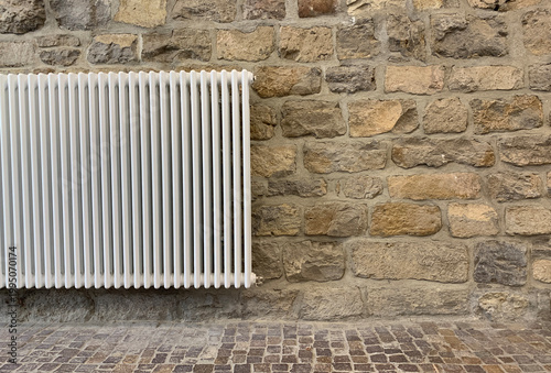 Cobblestone pavement and stone wall with heating radiator. Traditional European texture, rustic outdoor
