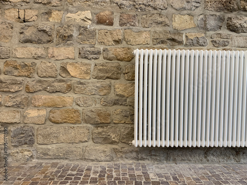 Heating radiator on a stone wall in a rustic interior. Minimal home heating concept with natural textures
