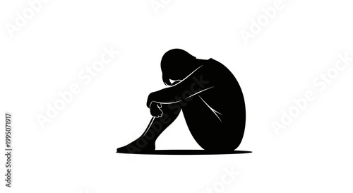 Silhouette of a person sitting with knees drawn up appearing dejected