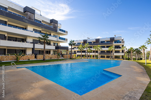 Photos Modern apartment complex with large swimming pool, sun terrace and palm trees in