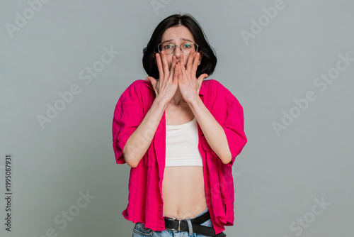 Obraz na plátně Young woman shivers hugs her shoulders and anxiously looks around, clearly expressing nervousness or fear