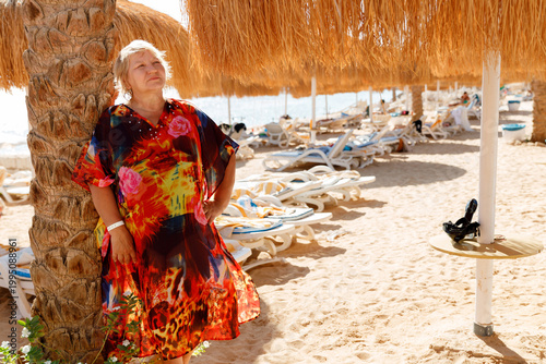 Beautiful senior woman enjoying summer holiday at tropical seaside resort. Retirement lifestyle, body positivity and active aging concept.