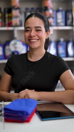 Young latina woman working as a shop assistant in a car parts store happily talking to the camera