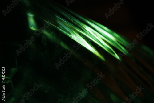 Quadro su tela Primer plano abstracto de un vaso de vidrio con bordes labrados, iluminado con luz verde intensa sobre fondo oscuro