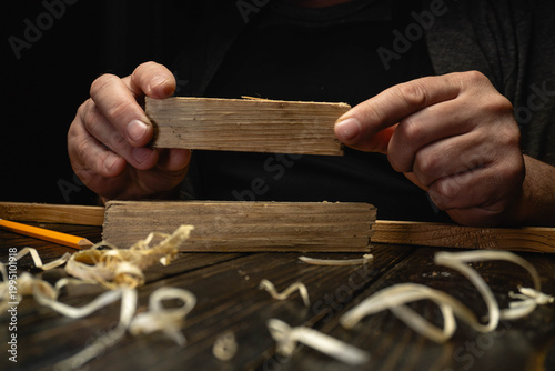 Tableau sur toile A person works with wood blocks and shavings on a wooden table
