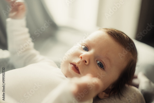 Baby lying on its back in the bright interior of the house, lifestyle shot in daylight