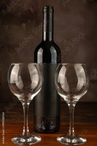 Bottle and wine glass, bottle and wine glass on a rustic wooden surface and abstract background, low key photo, selective focus.