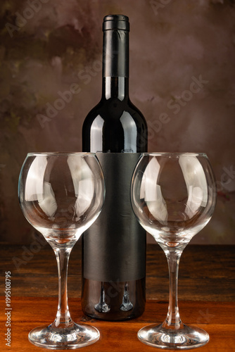 Bottle and wine glass, bottle and wine glass on a rustic wooden surface and abstract background, low key photo, selective focus.