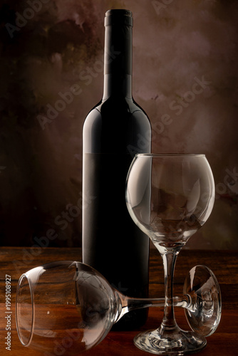 Bottle and wine glass, bottle and wine glass on a rustic wooden surface and abstract background, low key photo, selective focus.