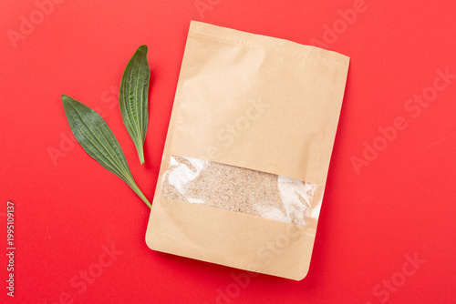 Psyllium husk powder with fresh leaves on color background, top view