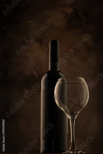 Bottle and wine glass, bottle and wine glass on a rustic wooden surface and abstract background, low key photo, selective focus.