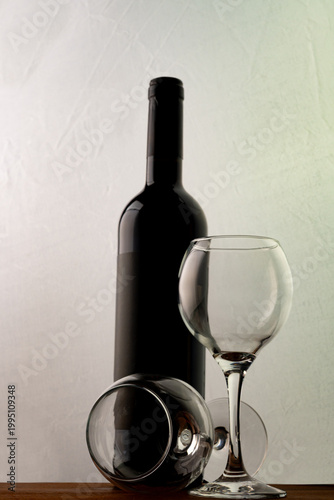 Bottle and glass of wine on a rustic wooden surface with a white background, selective focus.