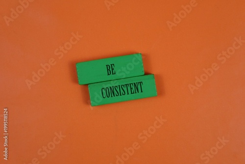 Foto Be Consistent Message On Green Blocks Over Orange Background For Motivation And