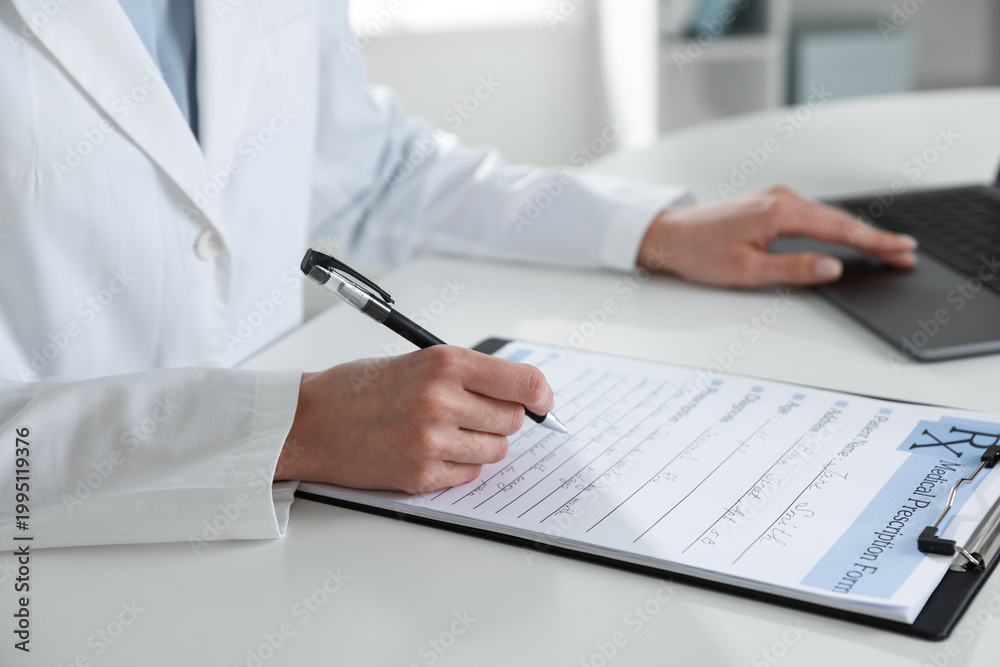 Fototapeta premium Doctor in medical coat working with clipboard and laptop at white table in clinic, closeup