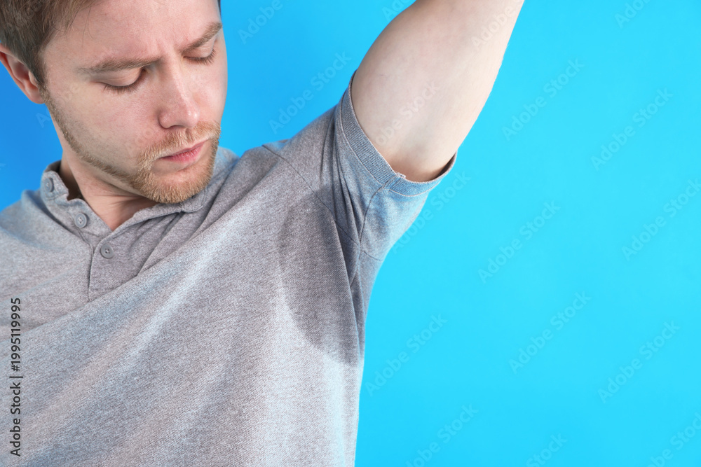 Naklejka premium Man with sweaty armpits on light blue background, closeup. Space for text