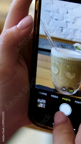 Woman photographing coffee in cafe pink white flowers social media food photography closeup