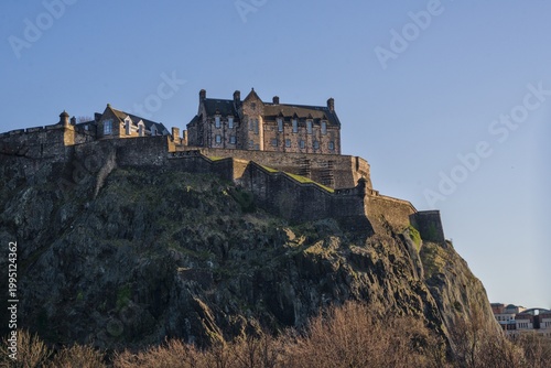 Cuadro en lienzo Edinburgh Castle perched dramatically on volcanic rock under a warm golden sky at dusk or sunset, Scotland