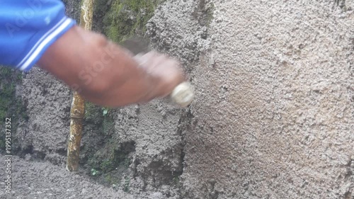 A construction worker is plastering a wall using a cement trowel on a house wall.