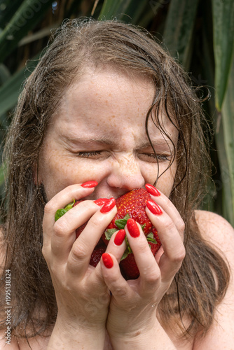Young woman passionately biting a strawberry