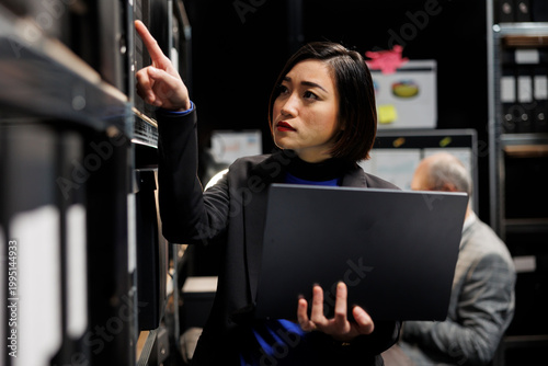 Fényképezés Asian private investigator in criminal cases archival depository office looking for criminal case paperwork on cabinet shelves