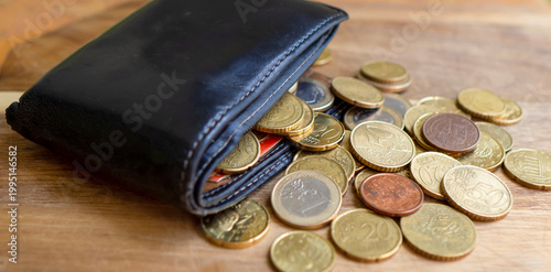 An old wallet with scattered coins on a blurry background.