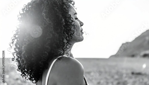 Woman with curly hair enjoying serene landscape.