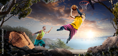 Basketball. Two basketball players practice on a basketball court in the wilderness. A beautiful landscape is in the background.