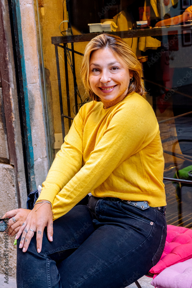 Fototapeta premium Happy woman in yellow sweater smiling outdoors in city