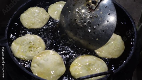 Crispy puris are being fried in hot oil for eating. Puri, potato and flour mixing snack recipe.
