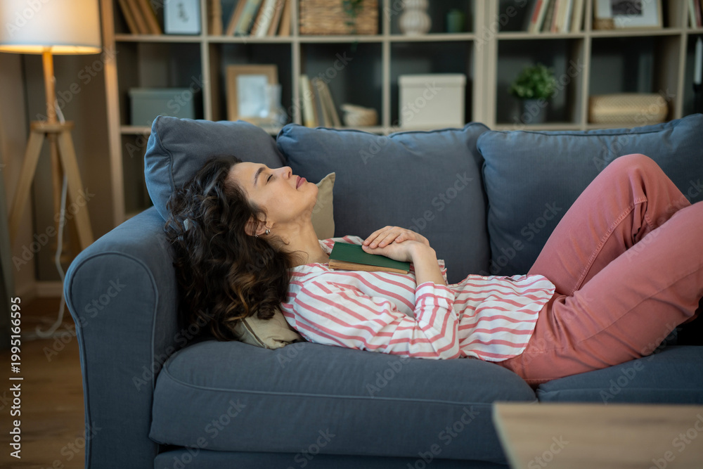 Obraz premium Woman relaxing on sofa after reading a book