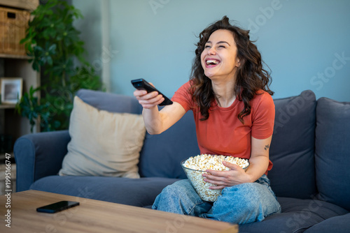 Obraz na plátně Happy woman laughing watching television holding popcorn and remote