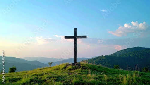 A solitary cross stands atop a grassy hill against a vast sky.