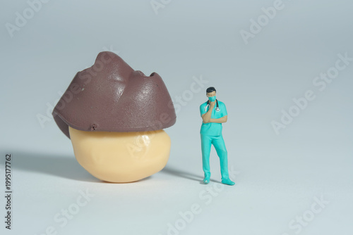 Miniature people toy figure photography. A men doctor or nurse thinking while standing in front of liver and gastric organ. Isolated grey background