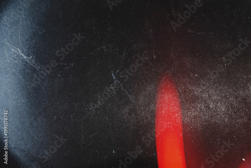Subtle red light leak on dark grainy and scratched film texture