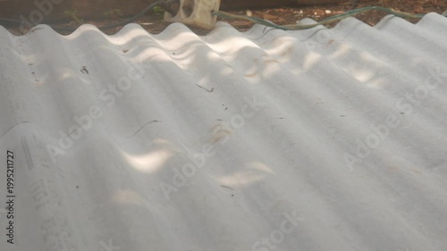 A construction worker uses a hand grinder to cut asbestos or fiber cement roofing sheets.